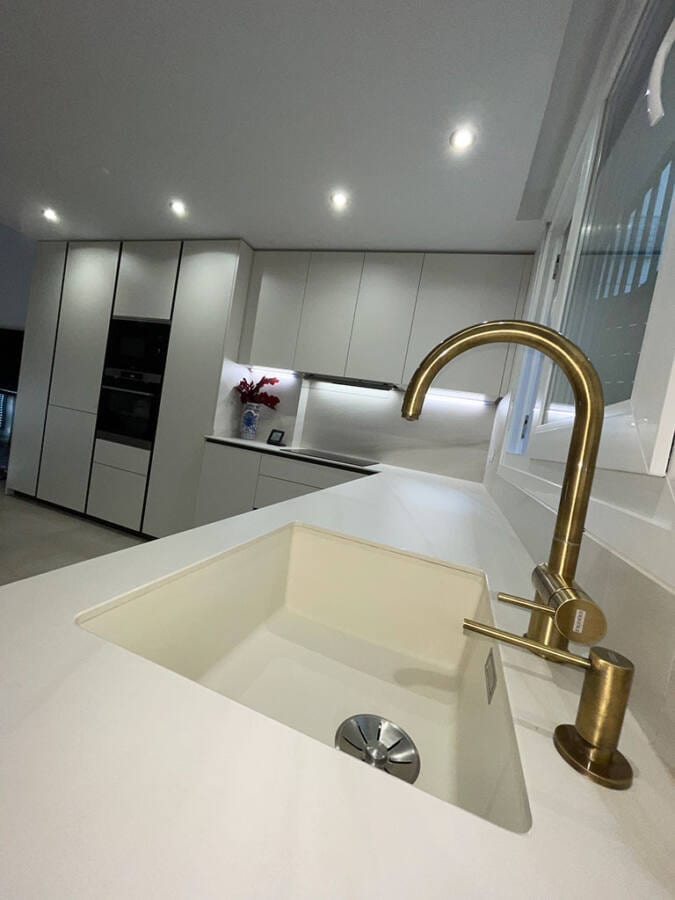Grifo de cocina de color dorado con fregadero sobre una encimera de mármol  espacio de trabajo cómodo y hermoso diseño interior de cocina moderno